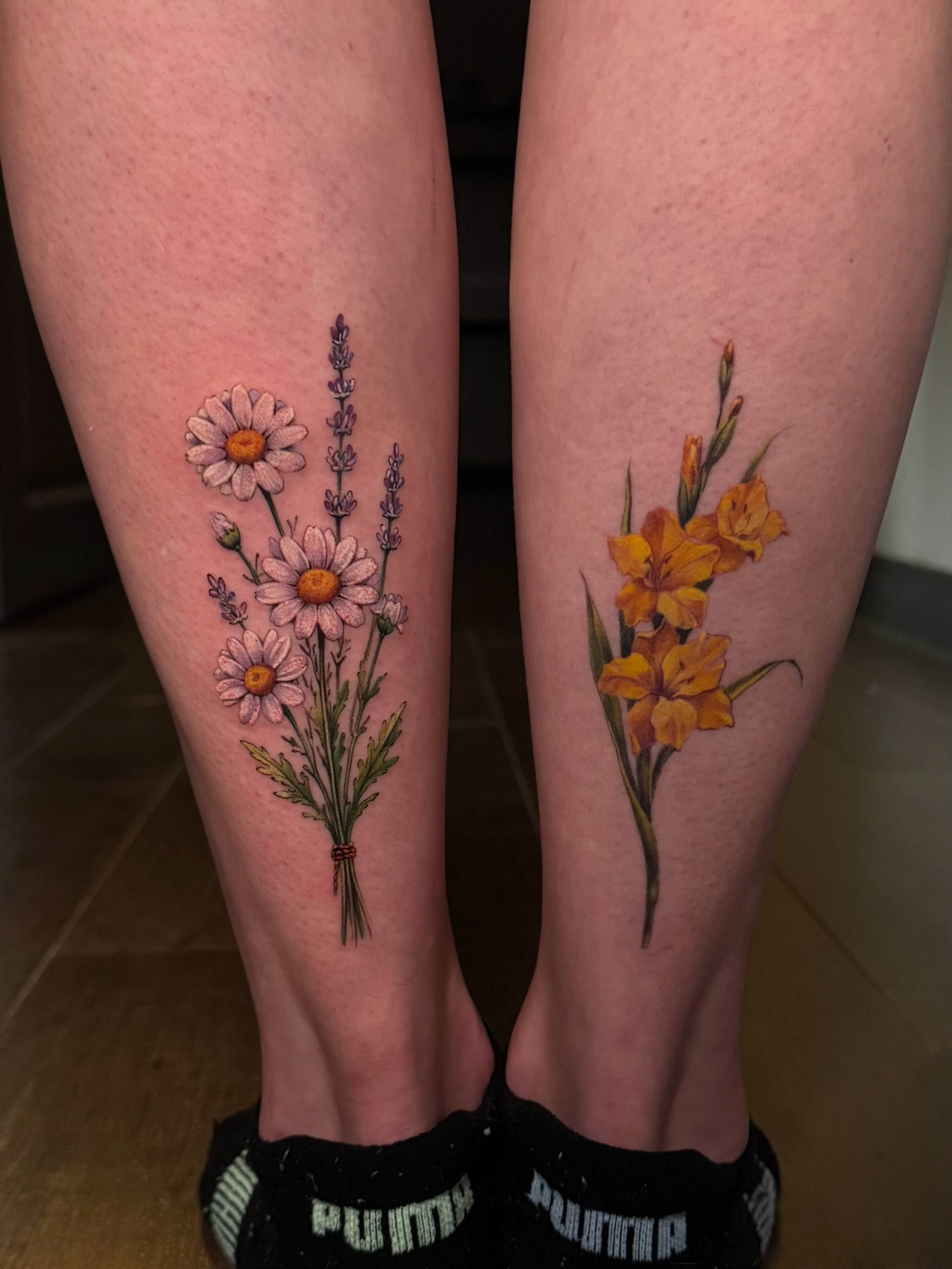 Fresh daisy bouquet tattoo beside healed floral work by Julia Luniko in Winnipeg