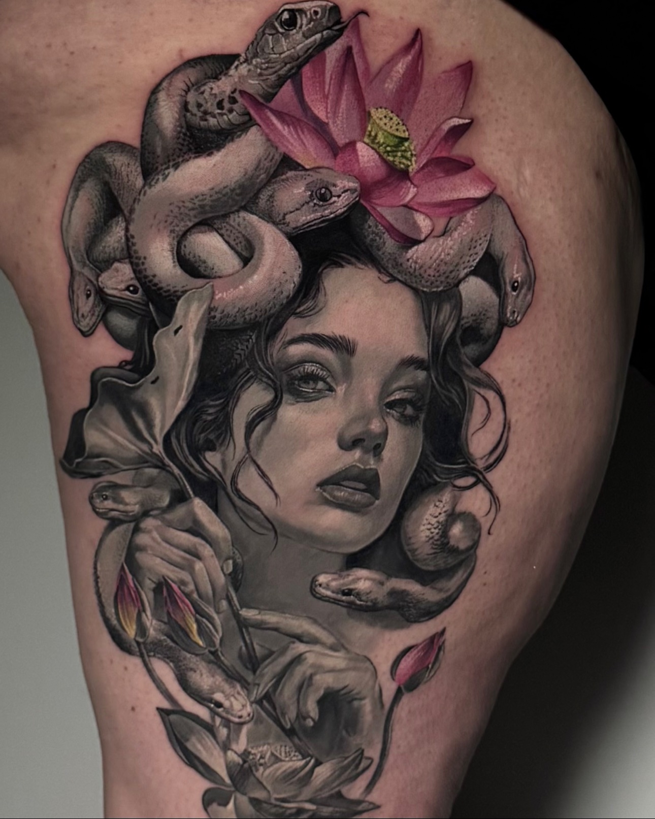 Black-and-grey realism Medusa tattoo with coiling snakes and pink lotus accents by Julia Luniko in Winnipeg